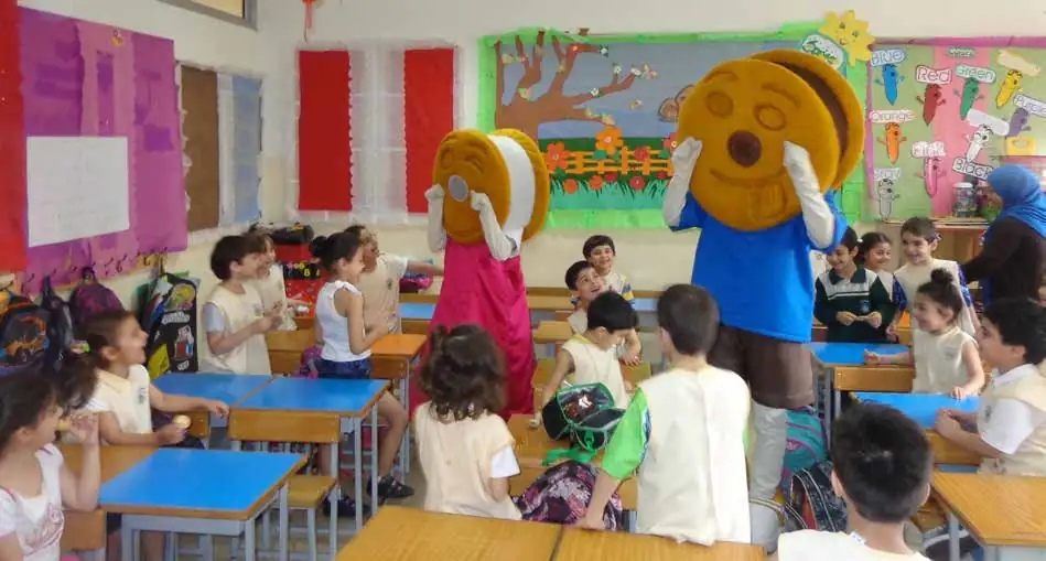Children in a classroom with two biscuit mascots during a school visit