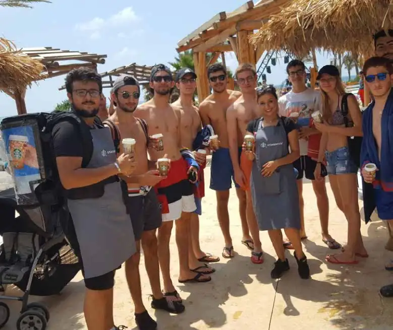 Beachgoers tasting Starbucks drinks from promoters with backpack dispensers