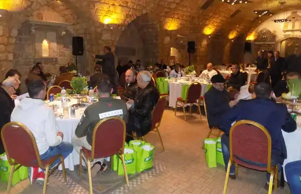 Guests at round tables during an iftar dinner in a stone-vaulted hall